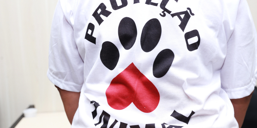 Foto das costas de uma pessoa vestida com uma camisa em que se lê "proteção animal"