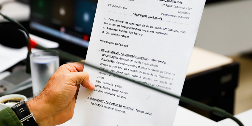 Mão de vereador segura pauta durante reunião da comissão