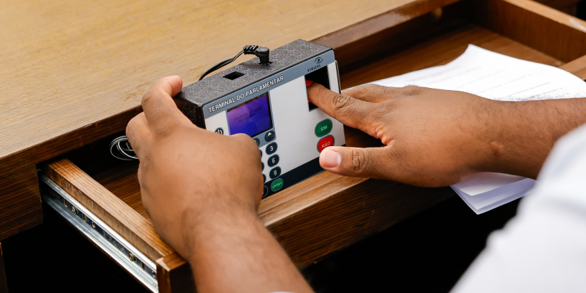 mãos de parlametar operando terminal de votação