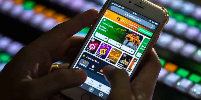 celular nas mãos de pessoa aberto em jogo de apostas