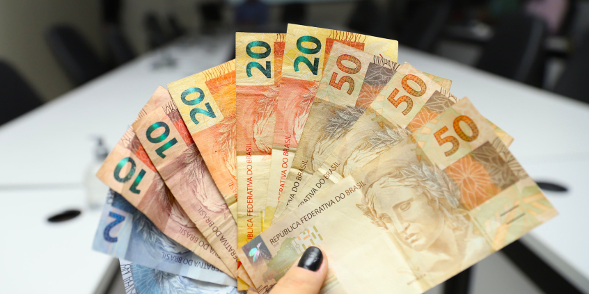 Pessoa segura várias notas de 20, 50 e 2 reais
