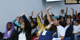 Jovens estudantes erguem os braços em votação
