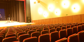 cadeira de teatro vazias e palco iluminado ao fundo