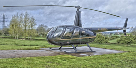 Helicóptero pousado em local cercado de grama. 