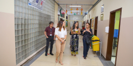As vereadoras Professora Marli e Marcela Trópia caminham pelo amplo corredor ao lado da diretora e do vice-diretorda escola. 