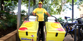 Homem usando uma blusa amarela e um boné segura dois carrinhos de sorvete, da mesma cor