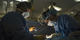 Foto mostra médicos operando paciente 