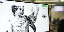 Imagem de mulher em Preto e Branco segurando uma balança, simbolizando a Justiça, é exibida na tela de um computador 