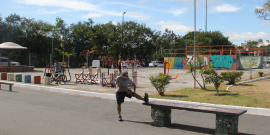 Dois homens se exercitam em Academia da Cidade, em local aberto, durante o dia.