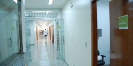 Corredor de posto de saúde, com homem de costas ao fundo 