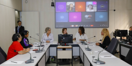 Vereadoras e convidadas participam de reunião no Plenário Helvécio Arantes. O telão atrás delas mostra convidadas presentes virtualmente.