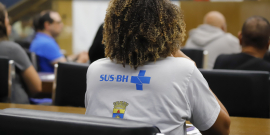 agente de saúde vista de costas acompanhando reunião em plenário da câmara municipal