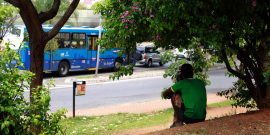 Homem em situação de rua sentado em meio à praça 