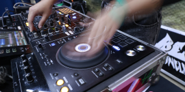Mãos de um DJ operam equipamento de som durante apresentação em reunião na CMBH