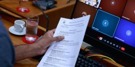 close nas mãos de parlamentar segurando pauta de reunião de comissão