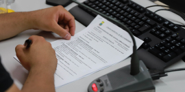 close nas mãos de parlamentar segurando pauta de reunião de comissão