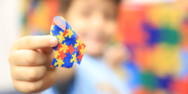 Criança mostra laço com o símbolo do autismo