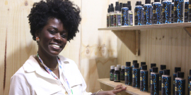 mulher negra ao lado de estanto com produtos cosméticos