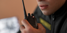 Homem segurando rádio usado por vigilantes