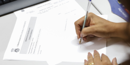 Mão de vereadora assina documento durante reunião da Comissão de Mulheres