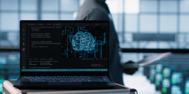 Computador em primeiro plano, com pessoa passando atrás