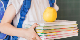 Menino com mochila carrega pilha de material didático