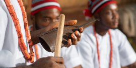 Instrumentos musicais em primeiro plano e pessoas com vestimentas afro
