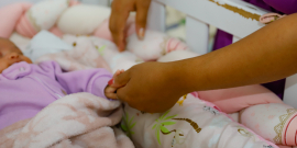 Pessoa mexe em bebê em berço