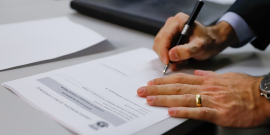mãos masculinas manuseiam documento segurando uma caneta