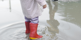 Criança com botas em poça de chuva