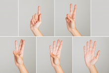 mãos exibem os sinais referentes à contagem de um a cinco em linguagem de sinais