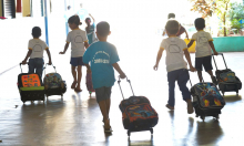 crianças de uniforme e mochilas chegando para aula, vistas de costas