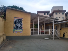 Parte interna do Centro de Esterilização de Cães e Gatos do Bairro Eplanada, com fachada amareça com a ilustração de um cão à esquerda e escada cinza com corrimão branco à direita.