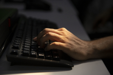 Imagem da mão de um homem caucasiano trabalhando no teclado de um computador