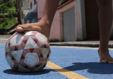 pés infantis jogando bola em rua de bairro, durante o dia