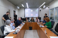Integrantes da reunião sentados em torno de uma mesa em formato de U, no Plenário Camil Caram