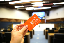 Imagem: detalhe de uma mão segurando o cartão bhbus dentro do Plenário da Câmara de BH