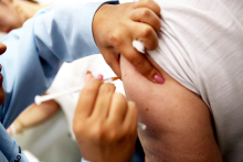 Pessoa caucasiana recebe uma vacina no braço esquerdo