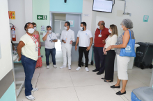 Oito pessoas de pé, reunidas no interior do Hospital Metropolitano Odilon Behrens, durante o dia.