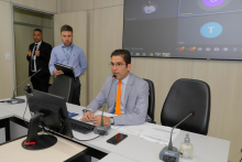 Parlamentar sentado à mesa, participando de reunião virtual com outros vereadores.