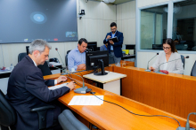 Vereadores discutem projetos no Plenário Camil Caram. O telão atrás deles mostra videochamada com vereadores presentes virtualmente.