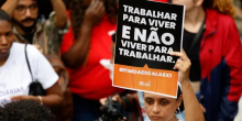 Manifestante mostra cartaz com os dizeres: "Trabalhar para viver e não viver para trabalhar"