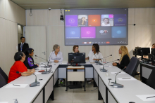 Vereadoras e convidadas participam de reunião no Plenário Helvécio Arantes. O telão atrás delas mostra convidadas presentes virtualmente.