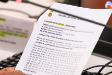 Mão segurando documento com pauta da reunião