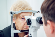 Senhora faz exame ocular com aparelho operado por médico