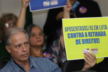 aposentados e pensionistas levantam cartazes e realizam manifestação