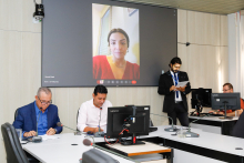 Vereadores no Plenário Helvécio Arantes; a tela atrás deles mostra vereadores presentes virtualmente