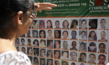 pessoa observa quadro com fotos de crianças desaparecidas