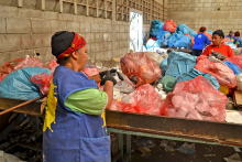 Mulher em frente a sacos de lixo reciclável